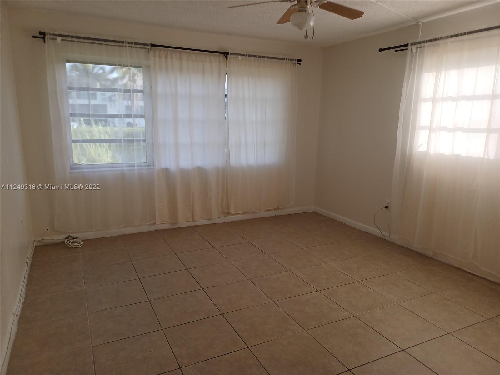 Andover Lakes Miami Gardens, FL 33179 - Photo 19 of 41 en empty room with windows and chandelier fan