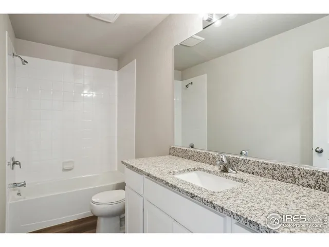a bathroom with a granite countertop sink a toilet and shower
