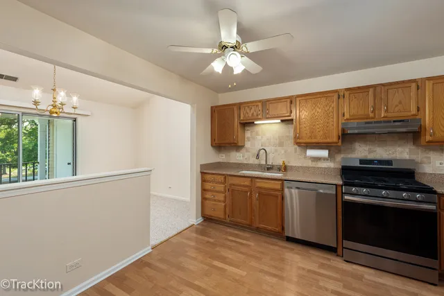 a kitchen with stainless steel appliances granite countertop a sink cabinets and wooden floor