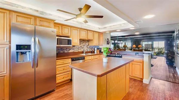 a kitchen with stainless steel appliances granite countertop a refrigerator a oven a stove and a sink with wooden floor