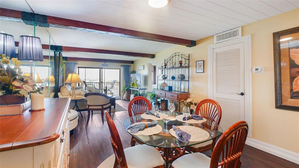 7150 Sunset Way, Unit 903E St. Pete Beach, FL 33706 - Photo 6 of 26 a dining room with furniture a chandelier and wooden floor