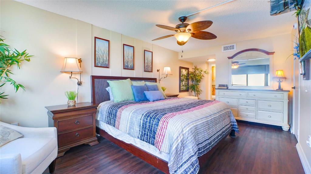 7150 Sunset Way, Unit 903E St. Pete Beach, FL 33706 - Photo 9 of 26 a bedroom with a bed and a chandelier