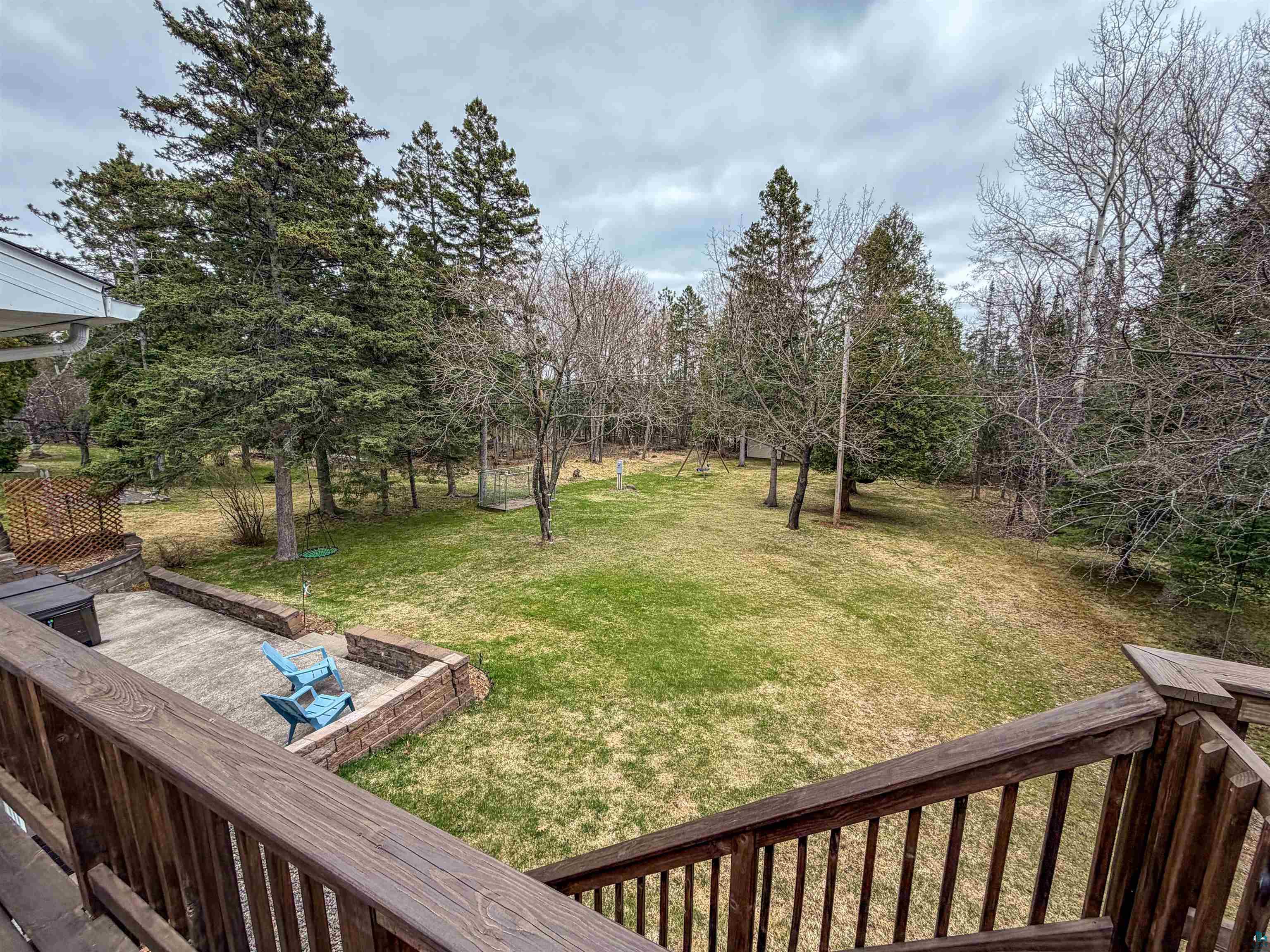 3704 Greysolon Road Duluth, MN 55804 - Photo 41 of 51 Expansive rear yard featuring mature evergreen trees, a manicured lawn, and a stone patio area with retaining walls