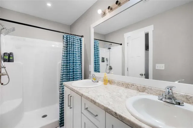 a bathroom with a granite countertop sink a shower and a mirror