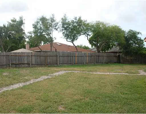 a view of a backyard with large trees and wooden fence