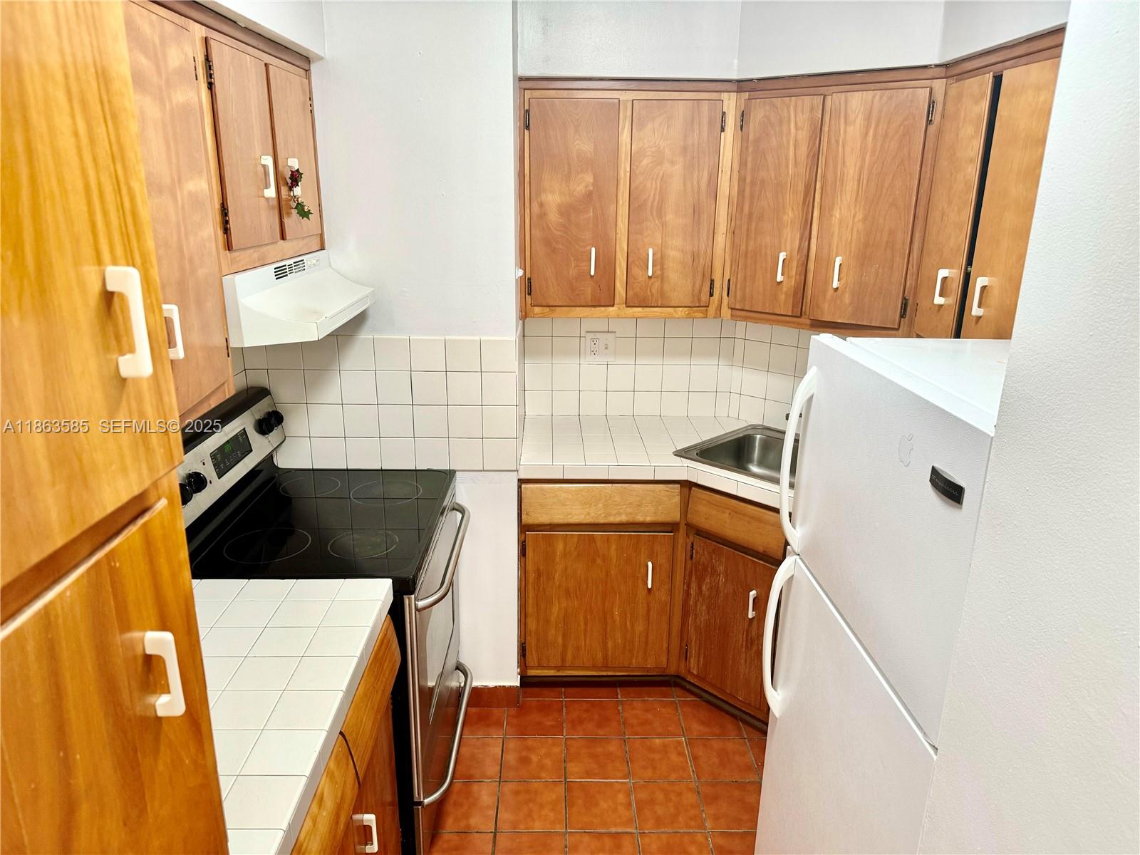 1430 Brickell Bay Drive, Unit 301 Miami, FL 33131 - Photo 8 of 18 a kitchen with a refrigerator a sink and cabinets