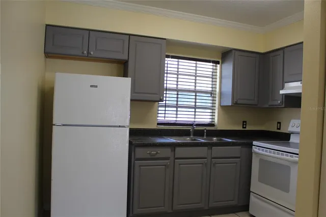a kitchen with a sink a refrigerator and cabinets