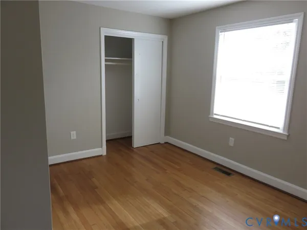 an empty room with wooden floor and a window