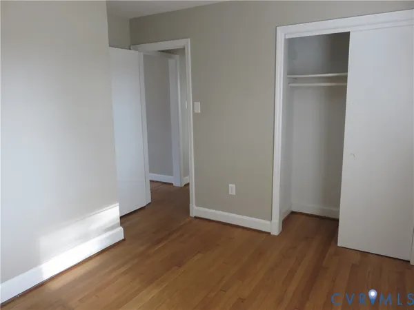 an empty room with wooden floor and closet