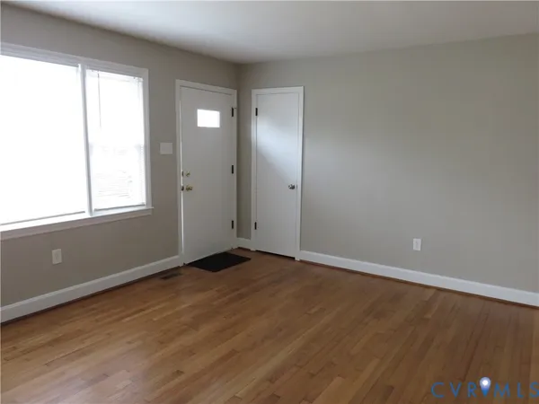 an empty room with wooden floor and windows