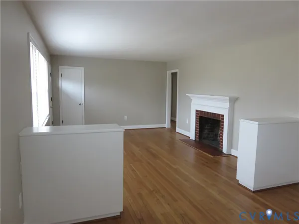 a view of empty room with wooden floor and fireplace