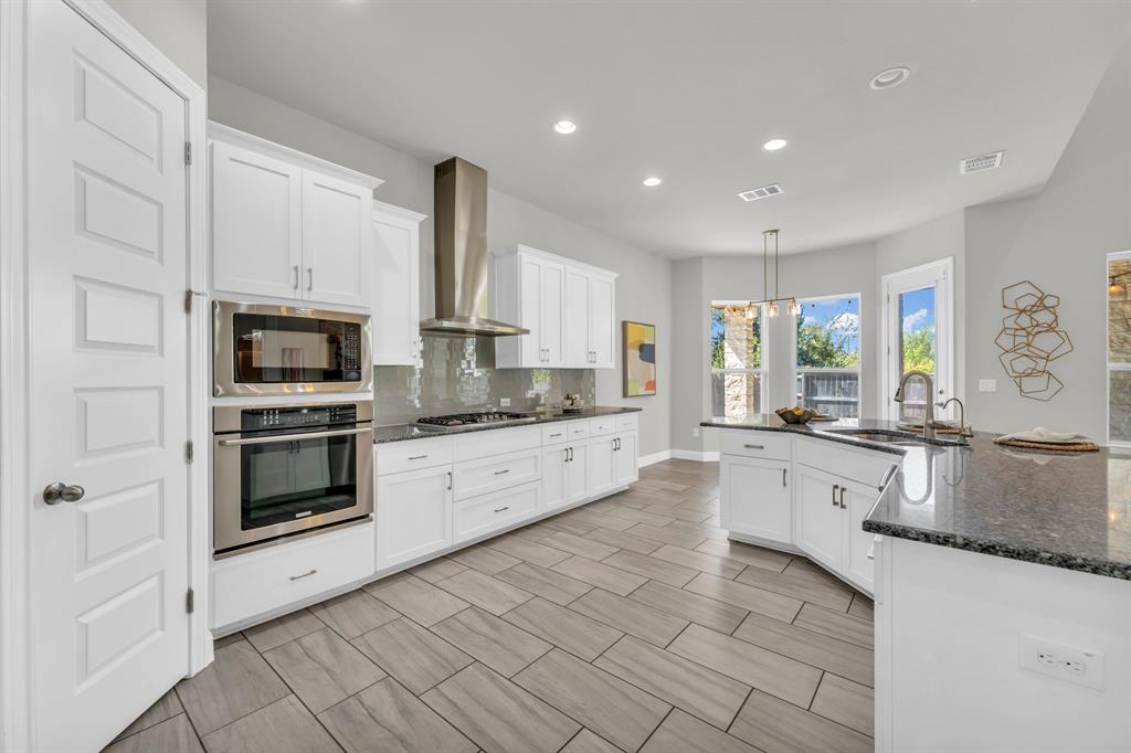 110 Magona Trail Georgetown, TX 78628 - Photo 12 of 38 A well-lit kitchen features modern appliances and a spacious island with granite countertops.