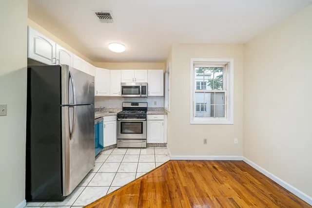 a kitchen with stainless steel appliances white cabinets white stove a microwave and a refrigerator
