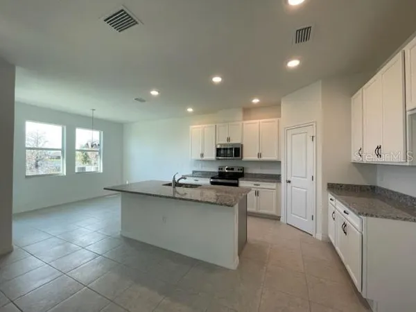 a kitchen with stainless steel appliances granite countertop a sink a stove a refrigerator a center island and a window