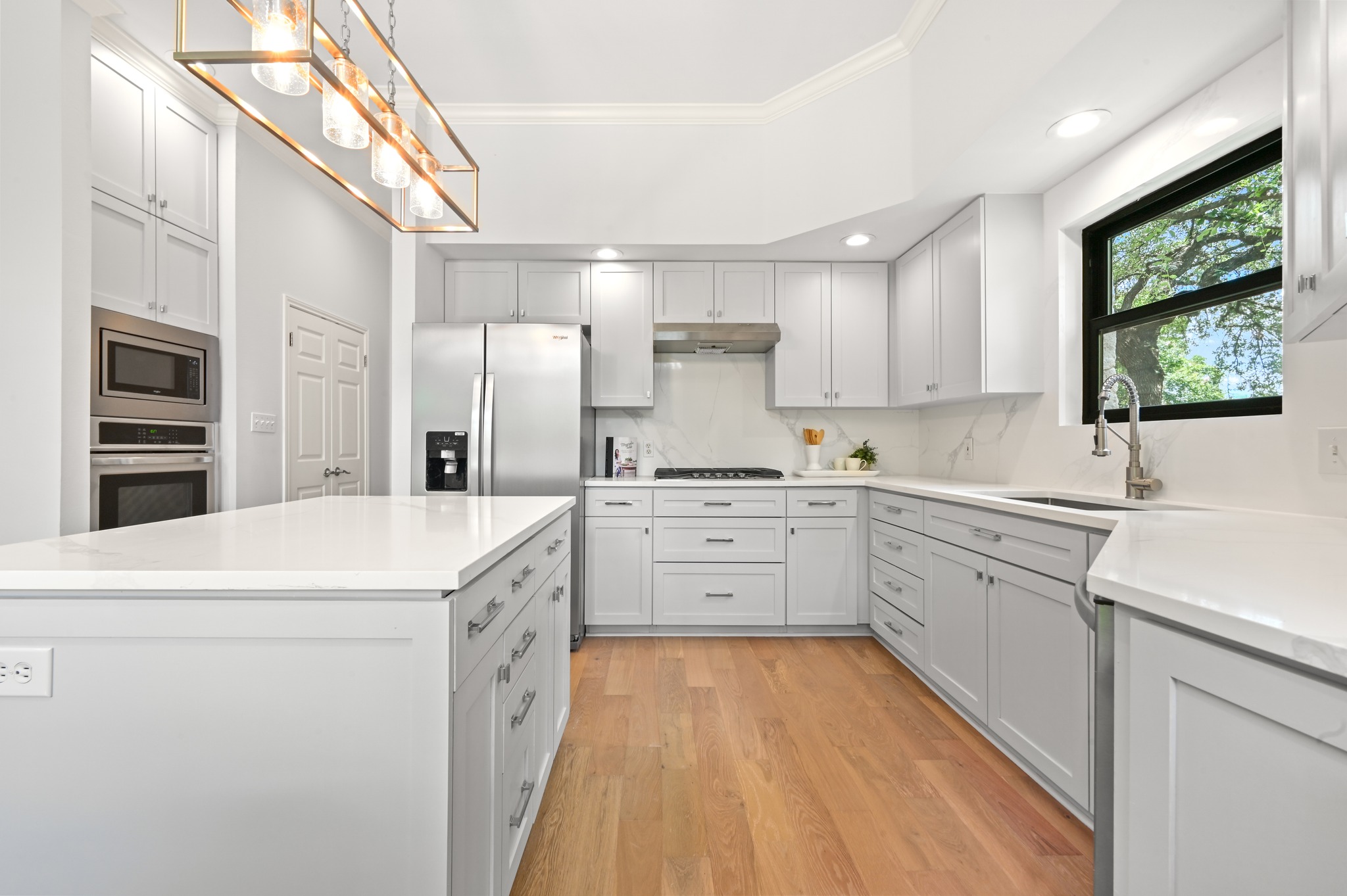 1107 Bowie Road Austin, TX 78733 - Photo 16 of 40 Culinary delights await in this bright kitchen with a spacious island, premium appliances, and warm wood flooring.