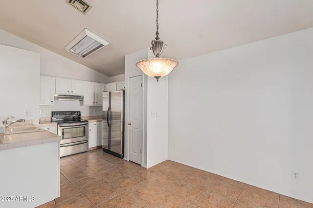 a kitchen with stainless steel appliances a stove a refrigerator and white cabinets