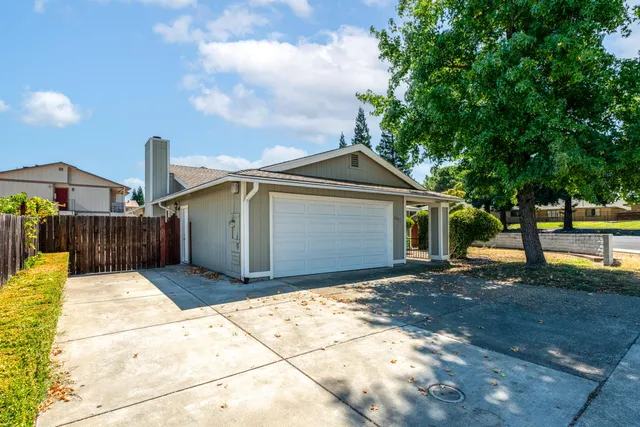 a view of a house with a yard and large tree