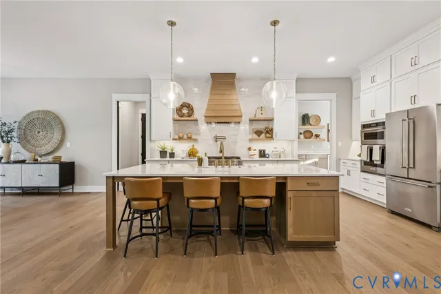 a kitchen with stainless steel appliances kitchen island granite countertop a dining table chairs and a refrigerator