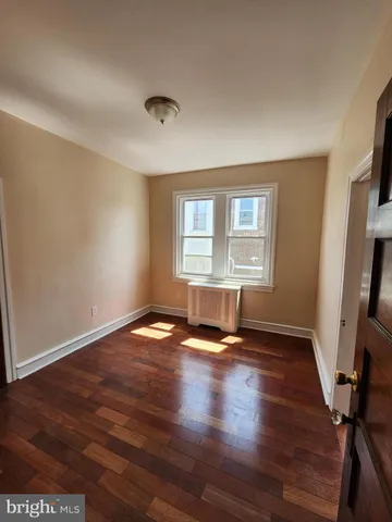 a view of a hallway with wooden floor and a bathroom