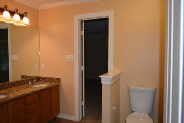 a bathroom with a granite countertop sink and a toilet