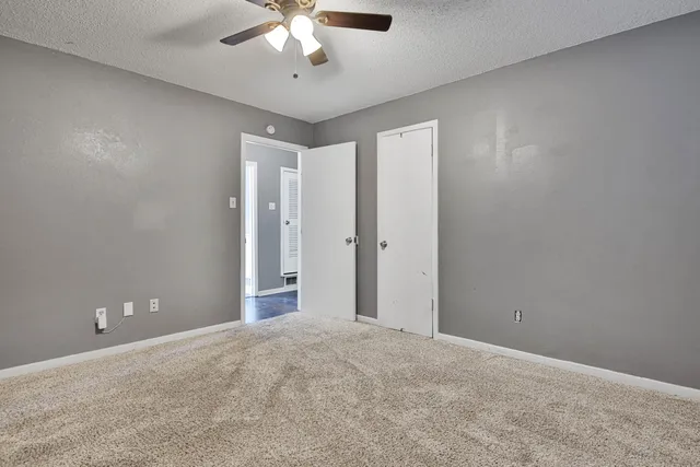 an empty room with a chandelier fan and windows