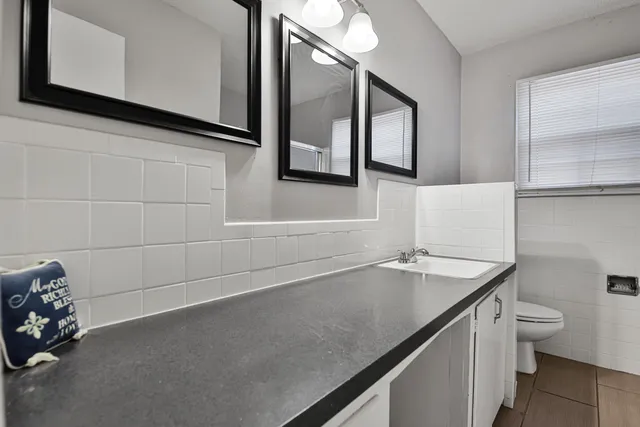 a bathroom with a granite countertop sink and a toilet