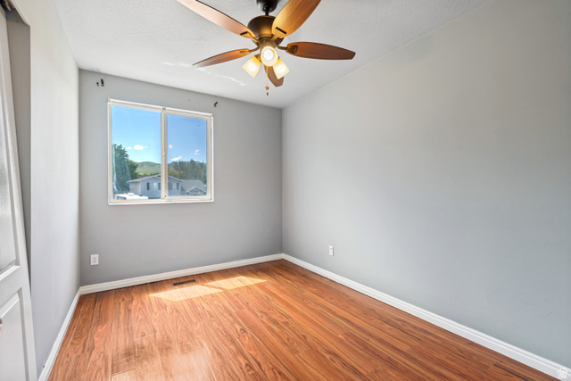 843 Deer Flat Road Tooele, UT 84074 - Photo 18 of 27 Room featuring wood-finish flooring, a ceiling fan with integrated lighting, a dual-pane window, and light grey wall finishes