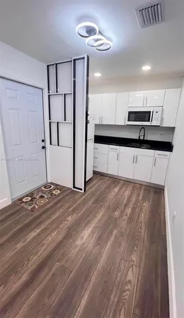 a kitchen with stainless steel appliances wooden floor and a refrigerator