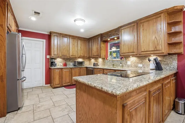 a kitchen with granite countertop a stove a sink and a refrigerator
