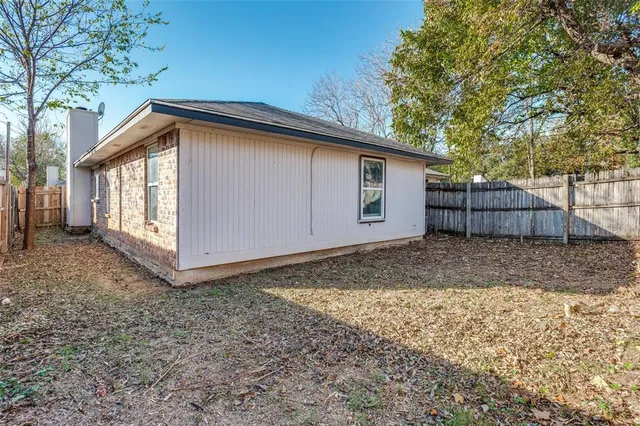 a backyard of a house with a large tree and wooden fence