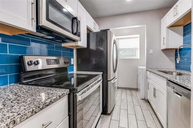 a kitchen with stainless steel appliances granite countertop a stove a sink and a refrigerator