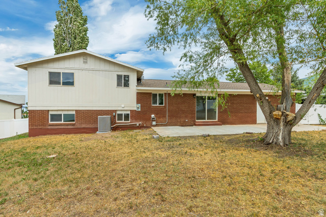 62 South Clark Lane Elk Ridge, UT 84651 - Photo 29 of 30 Rear exterior featuring brick and siding finishes, multiple windows, a ground-level patio, and a mature tree