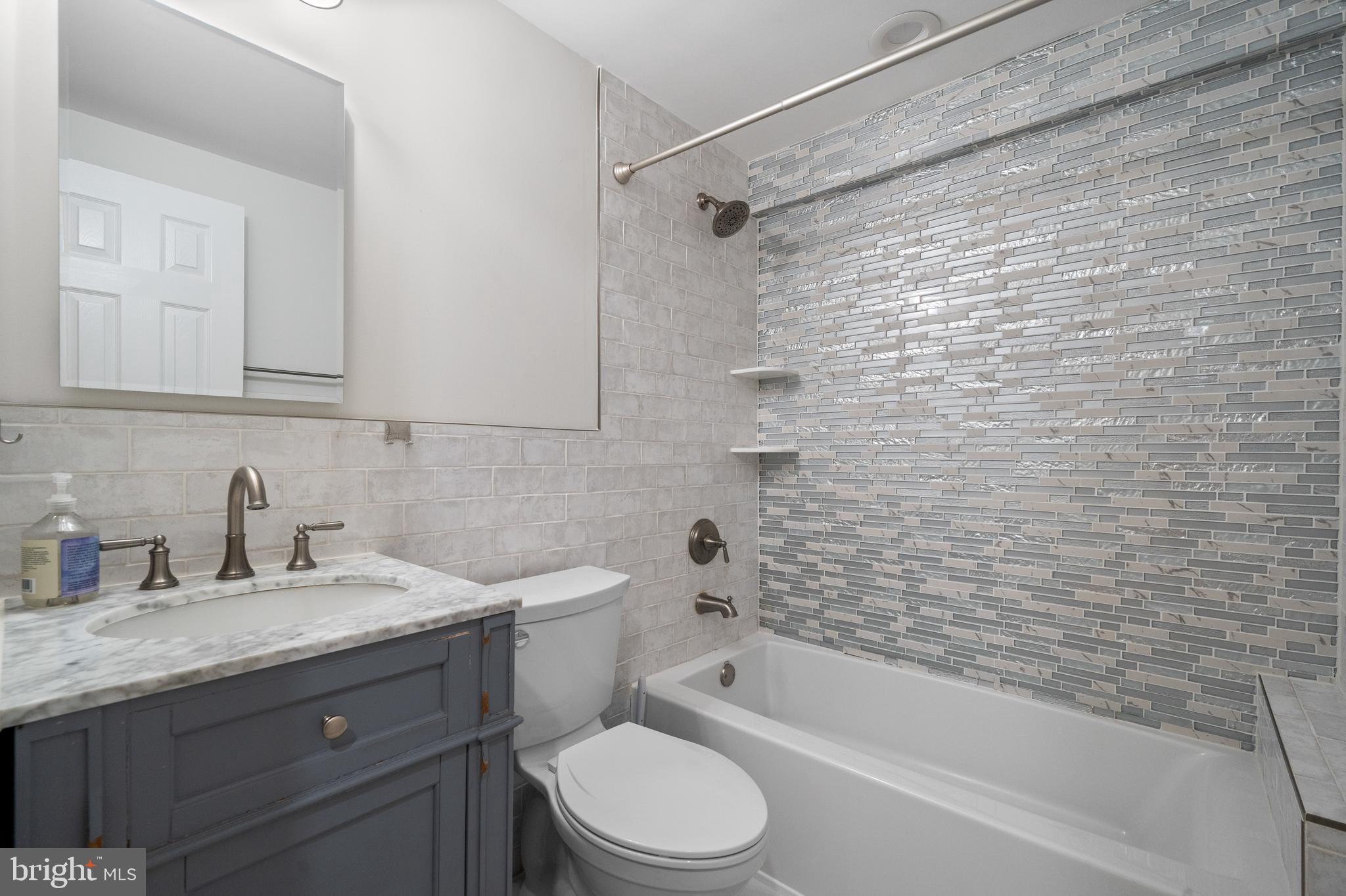 6119 Greeley Boulevard Springfield, VA 22152 - Photo 30 of 38 a bathroom with a granite countertop bathtub shower sink vanity and toilet