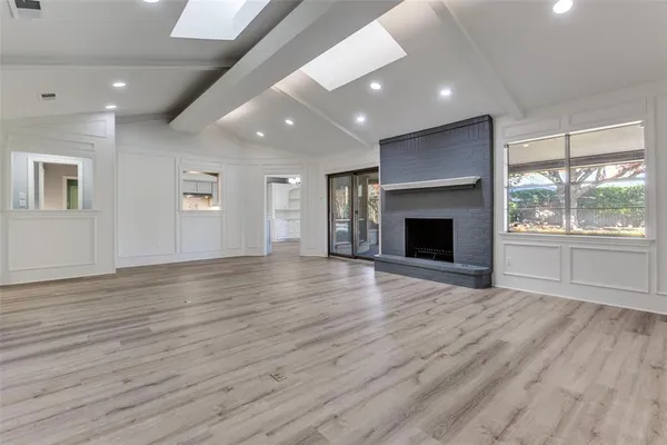 an empty room with wooden floor fireplace and windows