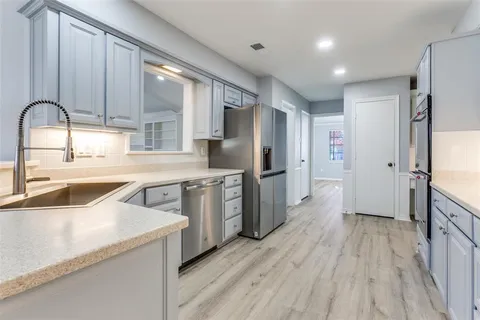 a kitchen with stainless steel appliances granite countertop a refrigerator a sink and wooden cabinets