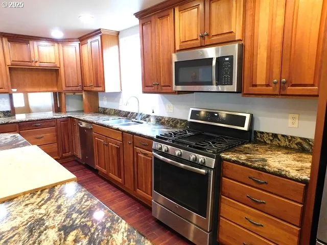 a kitchen with stainless steel appliances granite countertop a stove a sink and a microwave