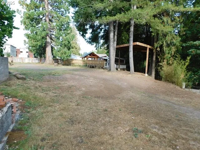 a view of a house with a yard and large trees
