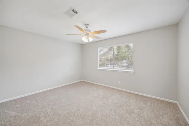 an empty room with ceiling fan and windows