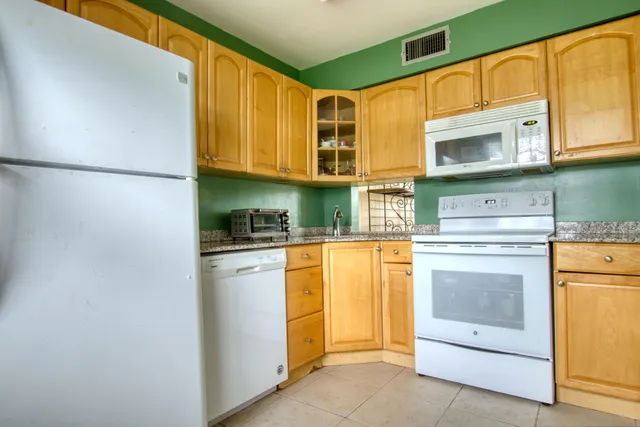 a kitchen with stainless steel appliances granite countertop a refrigerator and a stove top oven