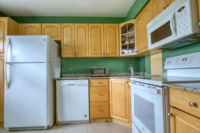 a kitchen with stainless steel appliances granite countertop a refrigerator a stove and a sink