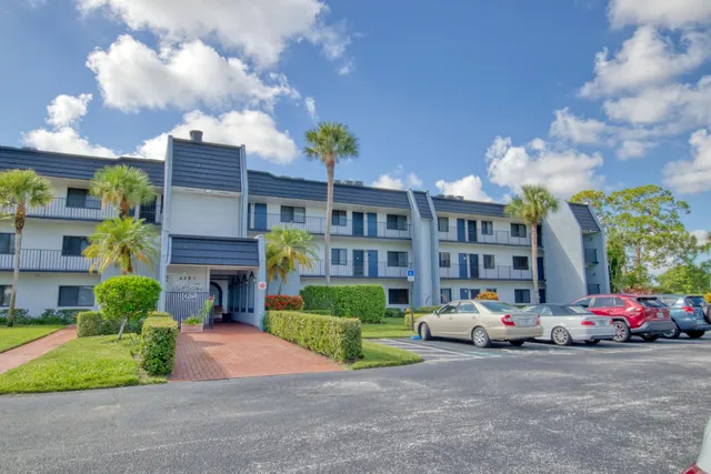 a front view of a building with cars parked