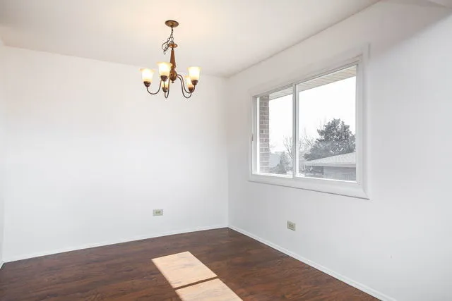 an empty room with wooden floor cabinet and windows