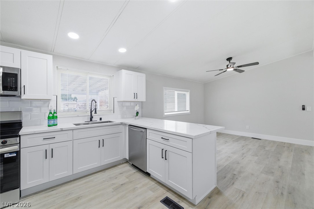 3940 Point Drive Pahrump, NV 89060 - Photo 15 of 35 A well-appointed kitchen boasts sleek white cabinetry, quartz countertops, and modern appliances, creating a welcoming culinary space.