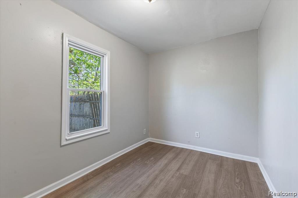 26076 Colgate Street Inkster, MI 48141 - Photo 13 of 24 Neutral tone walls with white trim, wood-finish flooring, a single window, and an overhead light fixture
