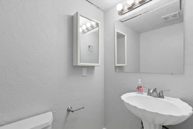 a bathroom with a sink a toilet and mirror