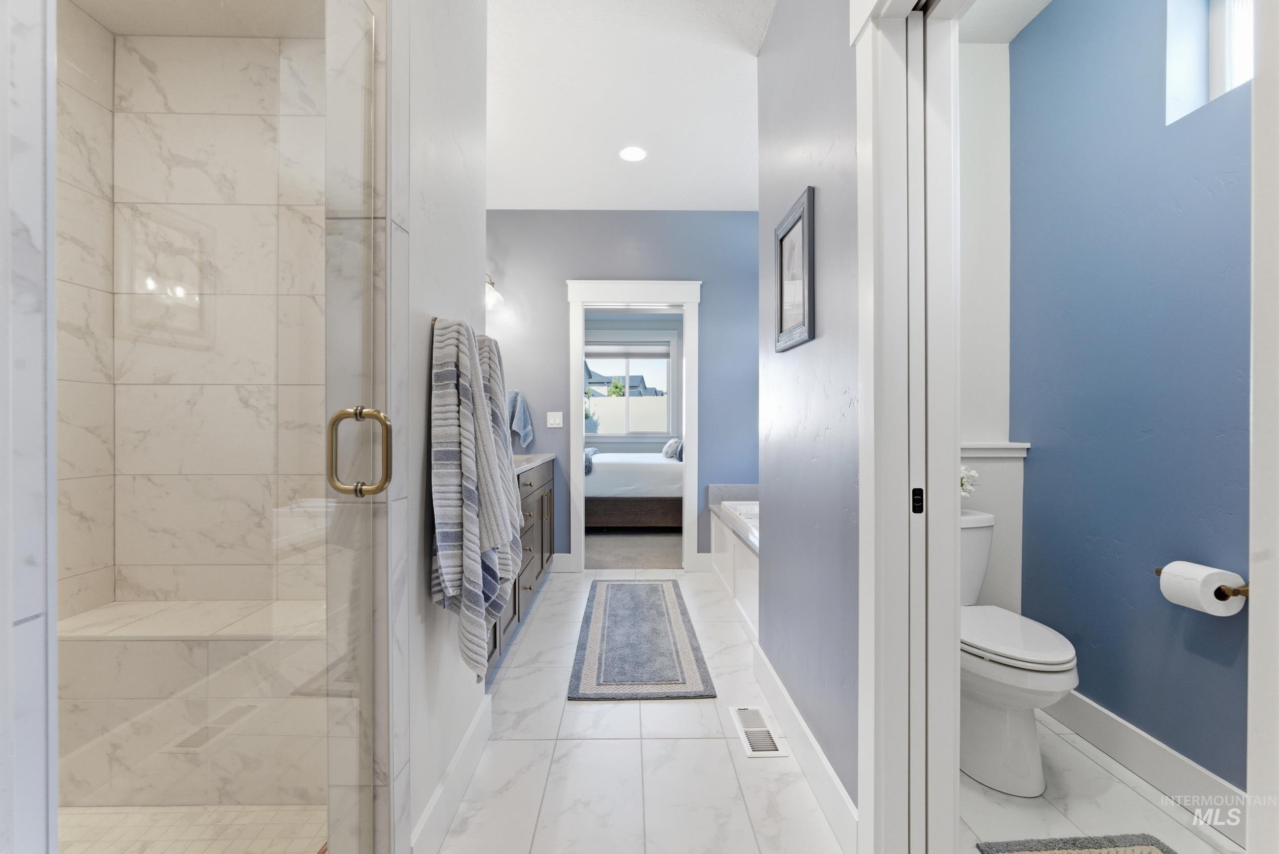 6347 South Utmost Lane Meridian, ID 83642 - Photo 25 of 37 Bathroom featuring a glass-enclosed shower with tile surround, a separate water closet with wainscoting, and tile flooring