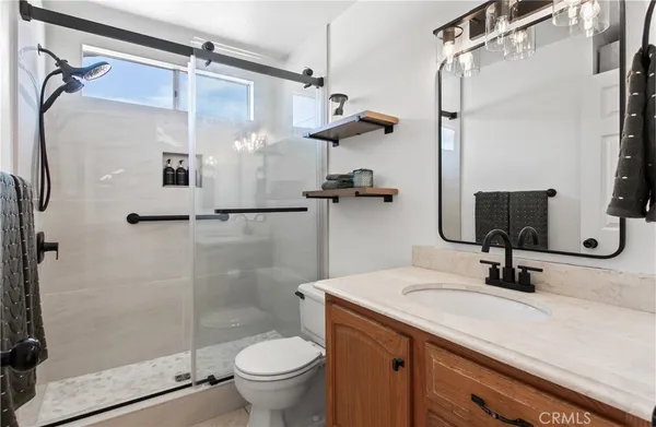 a bathroom with a sink vanity granite toilet and shower