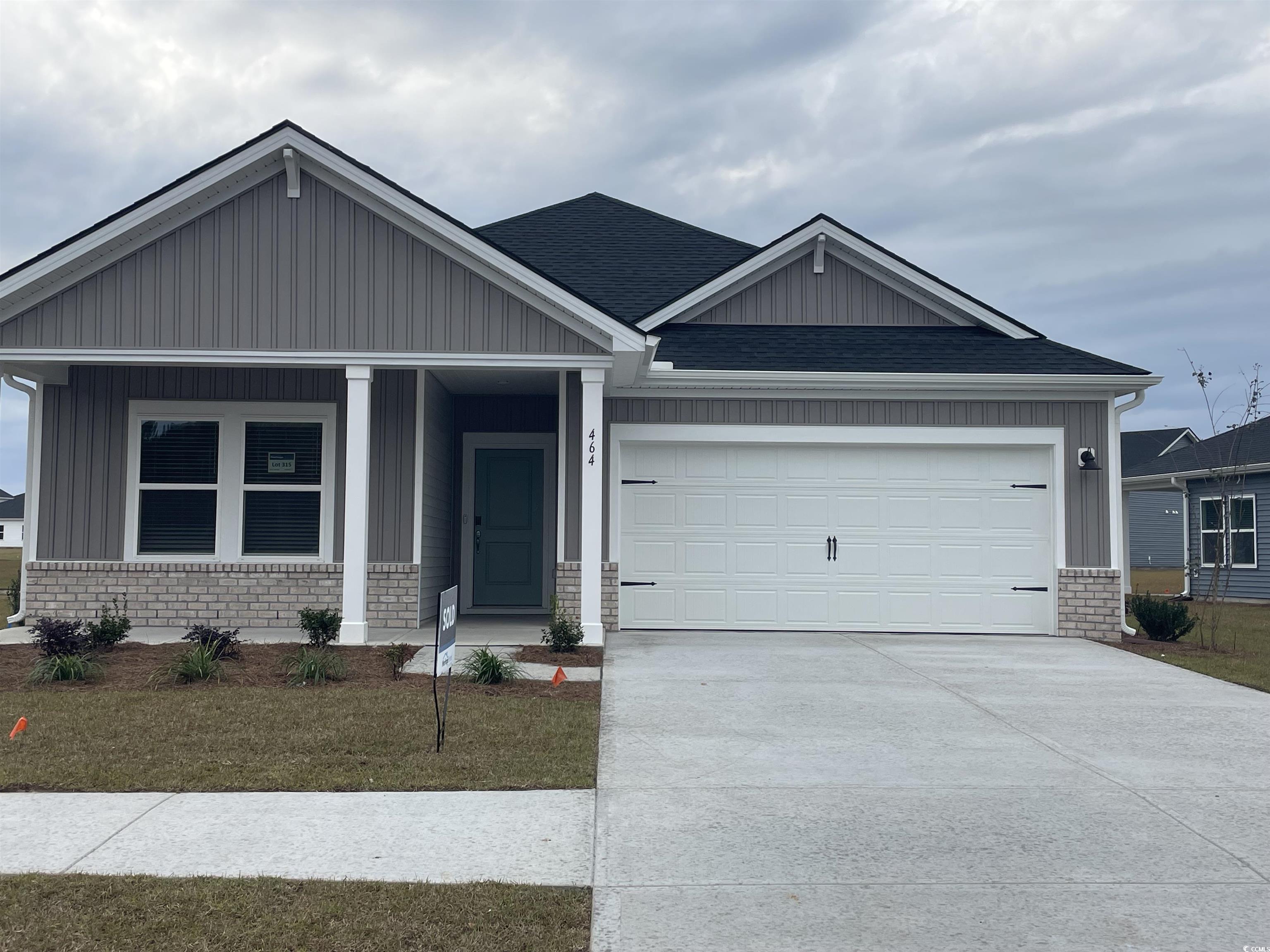 View of front of home with covered porch, brick siding, concrete driveway, and a garage