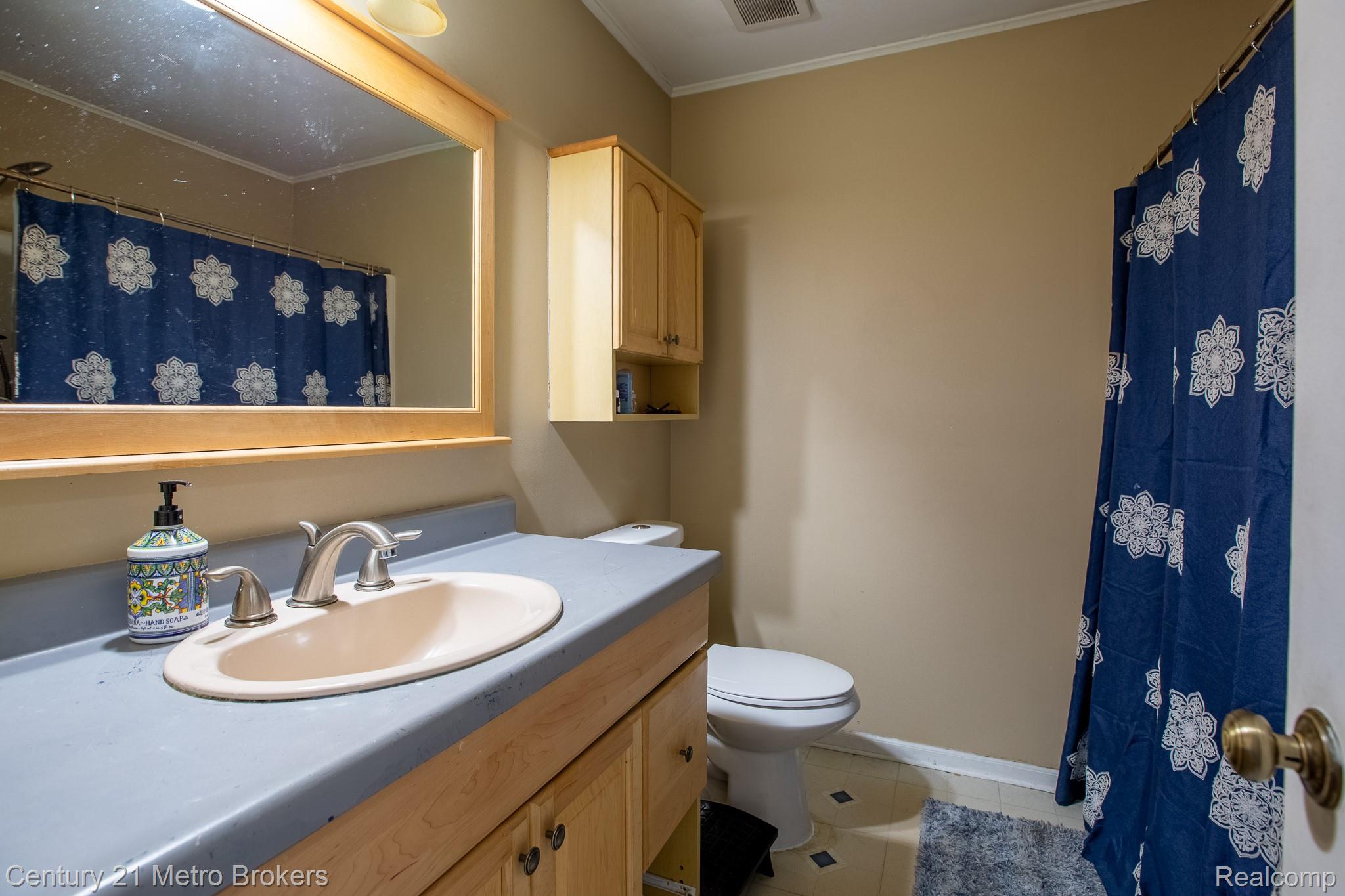 6101 Belsay Road Grand Blanc, MI 48439 - Photo 5 of 28 Bathroom with vanity, curtained shower, light tile patterned floors, and crown molding