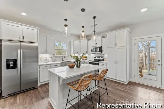 a kitchen with stainless steel appliances a refrigerator a sink a stove a dining table and chairs